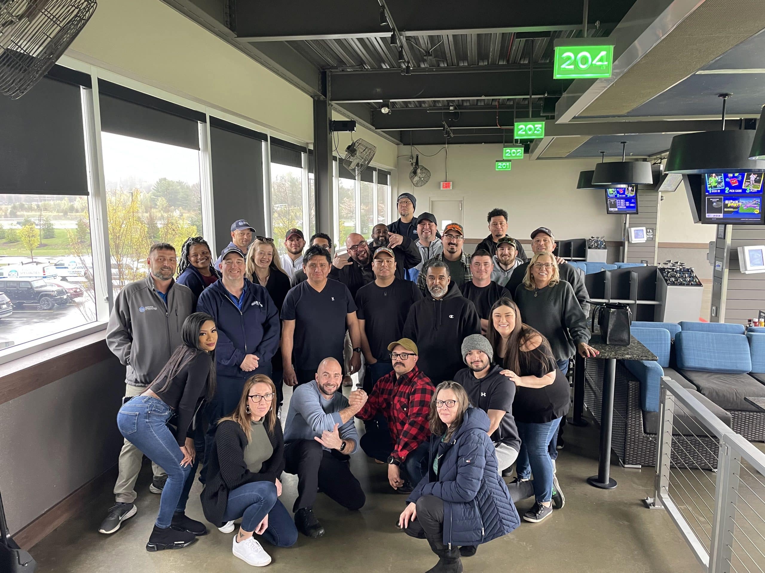 Group of SS team members posing together at an indoor company event venue