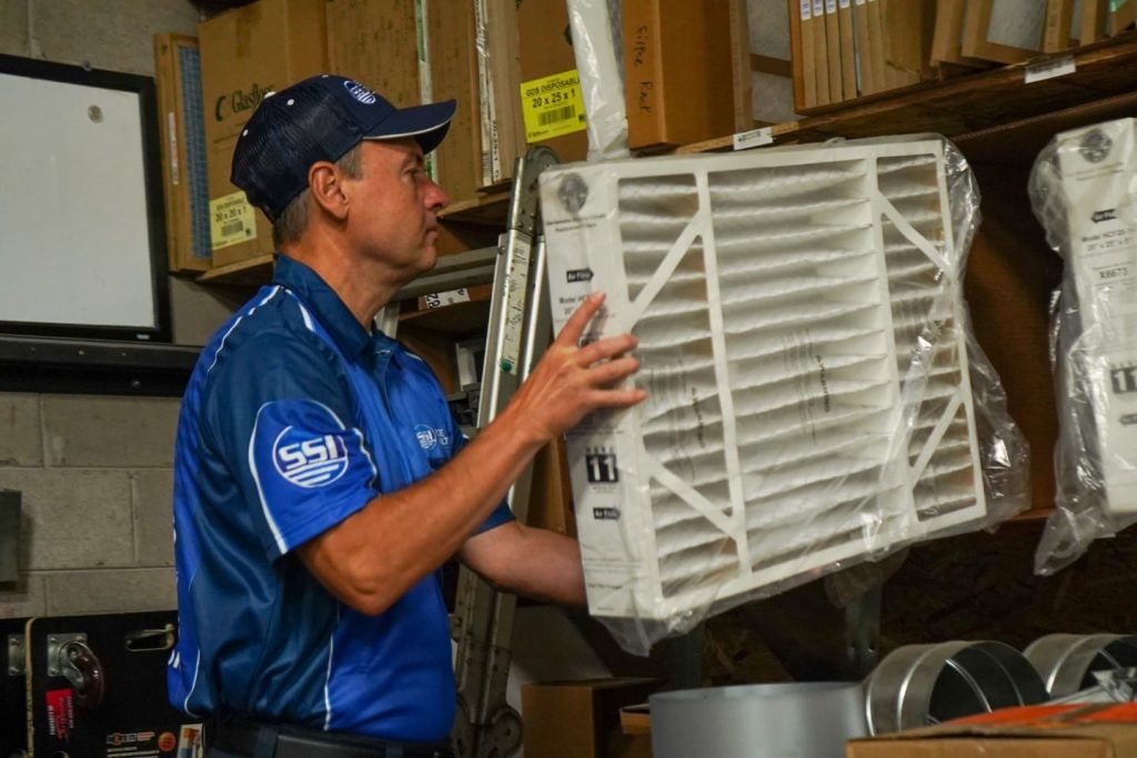 HVAC technician inspecting an air filter in a storage room.