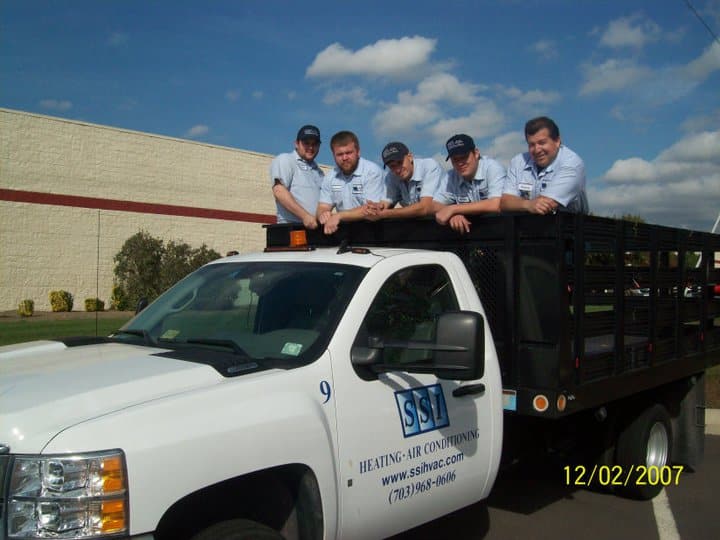 SS team members posing on and around a company truck under a blue sky