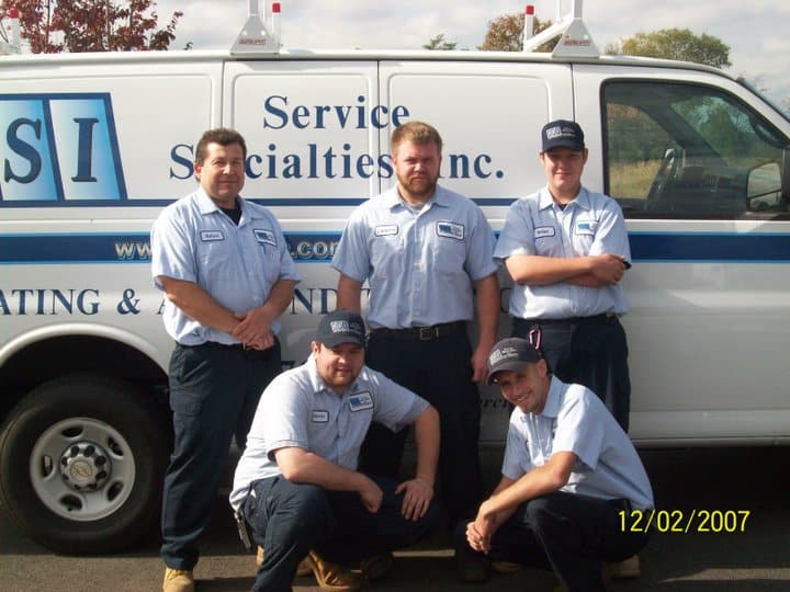 SSI technicians posing in front of a Service Specialties Inc. Inc. service van