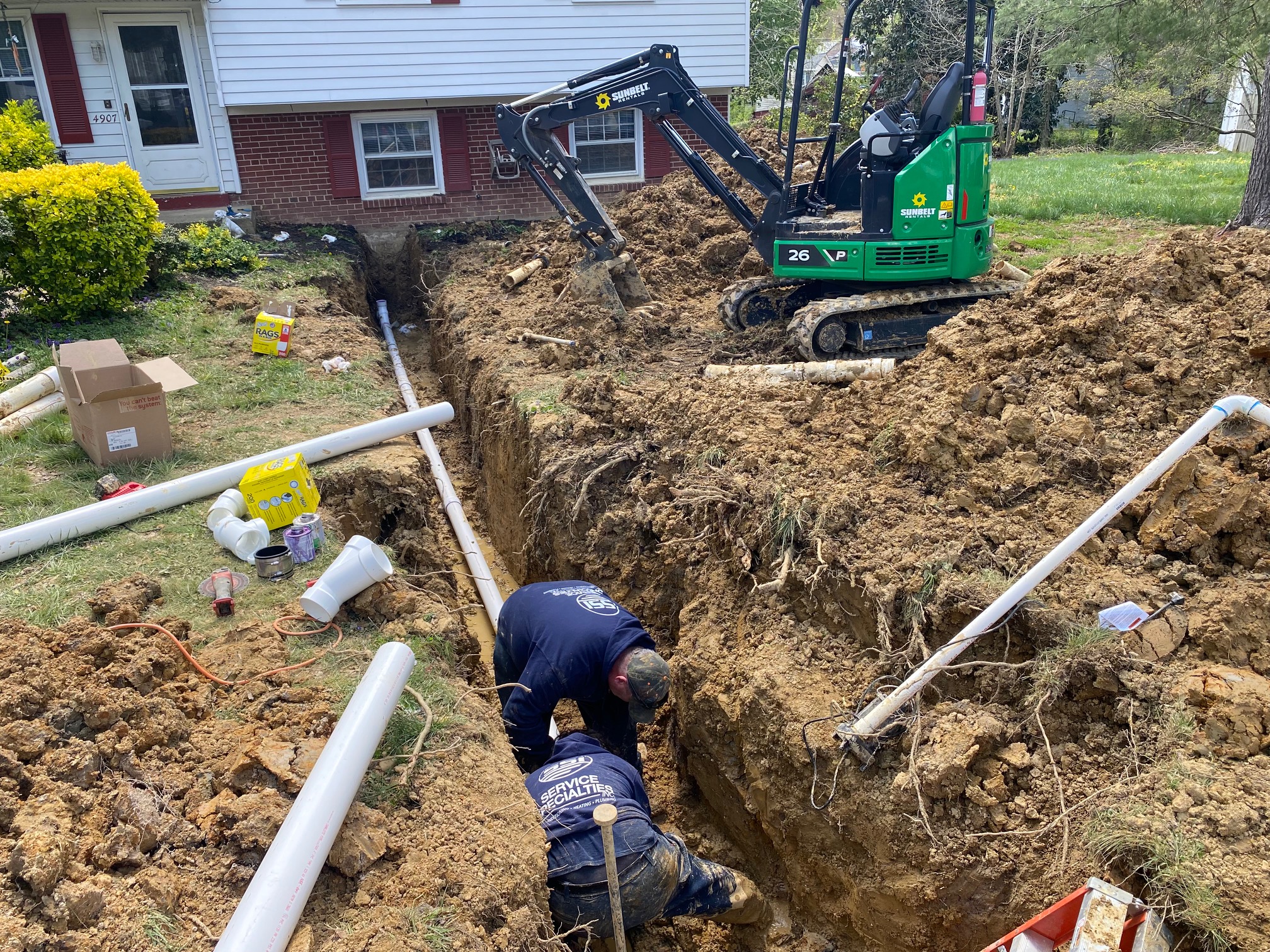 Worker operating mini excavator to dig in residential yard